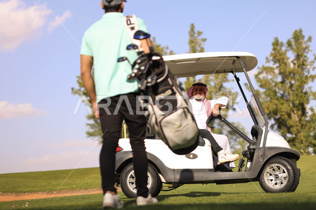 رجلان عربيان خليجيان سعوديان في ملعب الجولف، سيارة كهربائية مختصة بنقل الركاب، ممارسة لعبة الغولف على مساحات واسعة خضراء، أنشطة رياضية بالسعودية، لعبة الجولف، رياضات الألعاب الأولمبية الصيفية، أنشطة ترفيهية