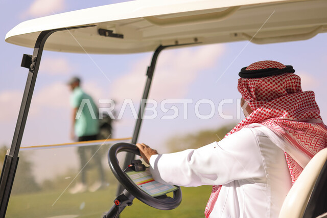 رجل عربي خليجي سعودي داخل سيارة كهربائية مختصة بنقل الركاب، ممارسة لعبة الغولف على مساحات واسعة خضراء، أنشطة رياضية بالسعودية، لعبة الجولف، رياضات الألعاب الأولمبية الصيفية، أنشطة ترفيهية، ملعب الجولف
