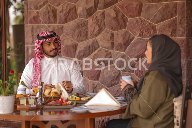 زوجان عربيان خليجيان سعوديان يستمتعان بتبادل الحديث  في احد المقاهي السعودية، تناول المشروبات الباردة، نقاشات وحوارات، قضاء أوقات ممتعة، أجواء عائلية سعيدة، مقهى سعودي