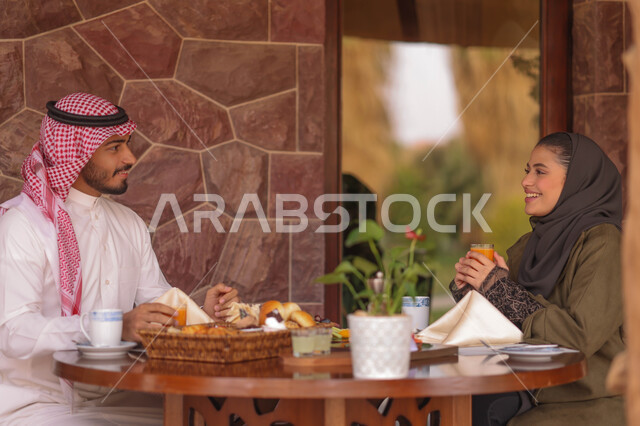 زوجان عربيان خليجيان سعوديان يستمتعان بتبادل الحديث  في احد المقاهي السعودية، تناول المشروبات الباردة، نقاشات وحوارات، قضاء أوقات ممتعة، أجواء عائلية سعيدة، مقهى سعودي