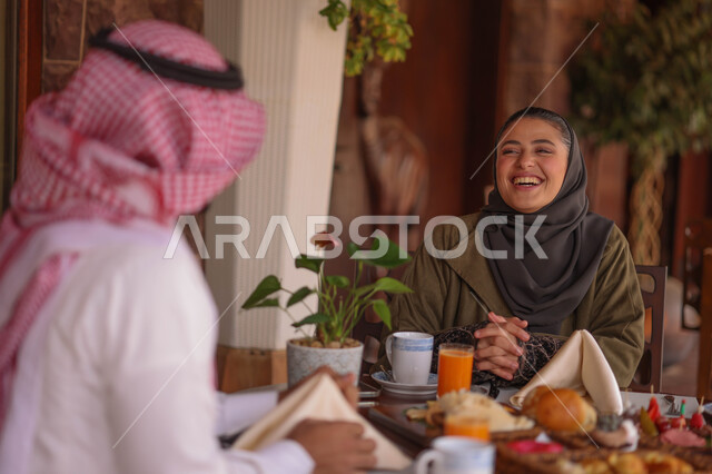 زوجان عربيان خليجيان سعوديان يستمتعان بتبادل الحديث  في احد المقاهي السعودية، تناول المشروبات الباردة، نقاشات وحوارات، قضاء أوقات ممتعة، أجواء عائلية سعيدة، مقهى سعودي