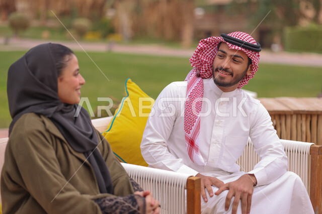 رجل وامرأة عرب خليجيين سعوديين يستمتعون بتبادل الحديث في احد الاماكن الترفيهية، نقاشات وحوارات، قضاء اوقات ممتعة، منتزهات سعودية، وناسة وتعارف، الجلوس في الهواء الطلق