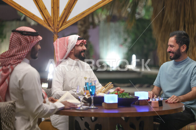 شباب عرب خليجيين سعوديين يستمتعون بتبادل الحديث في احد المقاهي السعودية، قضاء اوقات ممتعة، المشروبات الباردة، ديوانية شباب السعودية، نقاشات وحوارات، أجواء شبابية في مقهى سعودي