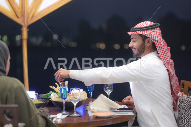 زوجان عربيان خليجيان سعوديان يستمتعان بتبادل الحديث  في احد المقاهي السعودية، تناول المشروبات الباردة، نقاشات وحوارات، قضاء أوقات ممتعة، أجواء عائلية سعيدة، مقهى سعودي