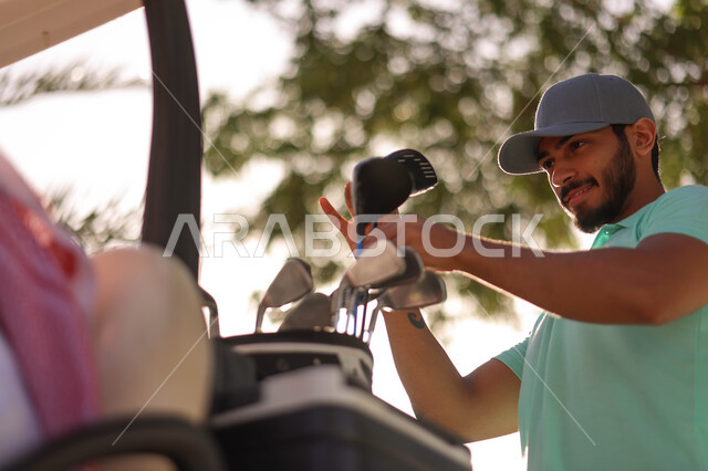 رجل عربي خليجي سعودي في ملعب الجولف، الإستعداد لممارسة لعبة الغولف، حقيبة الجولف، أنشطة رياضية بالسعودية، لعبة الغولف ( الجولف ) ، رياضات الألعاب الأولمبية الصيفية، أنشطة ترفيهية، ملعب الجولف