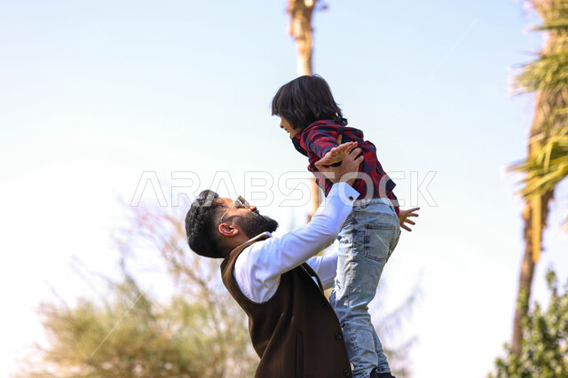 رجل عربي خليجي سعودي يقضي أوقات ممتعه مع ابنه، اللعب في إحدى الحدائق العامة, نزهه في الهواء الطلق،  الطبيعة الخضراء، أنشطة ترفيهية عائلية, عطله صيفيه