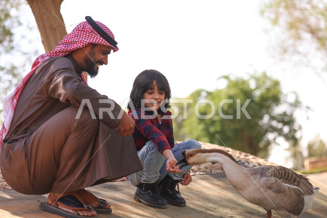 رجل عربي خليجي سعودي يقضي أوقات ممتعة مع إبنه في حديقة الحيوانات في المملكة العربية السعودية، أماكن سياحية ترفيهية بالسعودية، حيوانات برية في المحمية الطبيعية، فعالية سفاري موسم الرياض، فعاليات ترفيهية عائلية