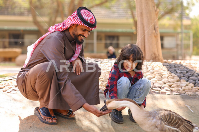 رجل عربي خليجي سعودي يقضي أوقات ممتعة مع إبنه في حديقة الحيوانات في المملكة العربية السعودية، أماكن سياحية ترفيهية بالسعودية، حيوانات برية في المحمية الطبيعية، فعالية سفاري موسم الرياض، فعاليات ترفيهية عائلية