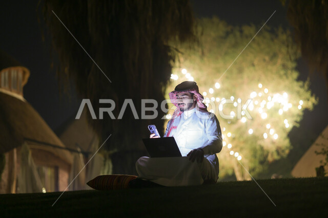 رجل عربي خليجي سعودي يستخدم الحاسوب المحمول، إنجاز مهام العمل، تصفح الإنترنت، العمل عن بعد، دردشة الكترونية، استخدام تقنيات حديثة، حدائق ومنتزهات