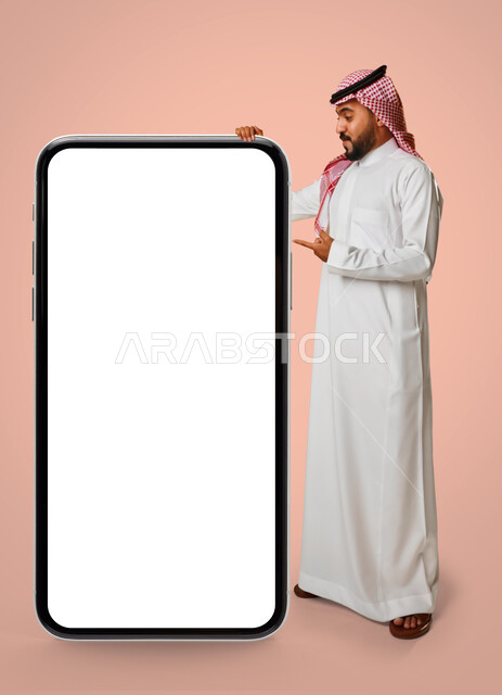 بورتريه رجل عربي خليجي سعودي ، عرض شاشة هاتف محمول كبير الحجم ،شاشة جوال مفرغة باللون الابيض ، متاجر تسوق الكترونية ، تقنيات و تكنولوجيا ، التسويق الإلكتروني ، خلفية زهرية.