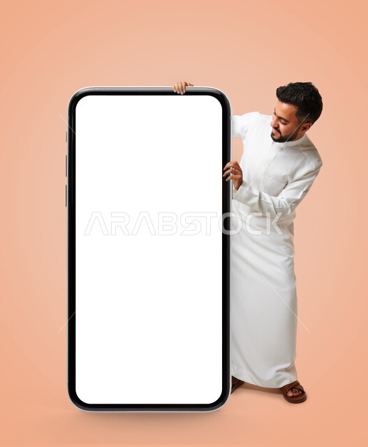 بورتريه رجل عربي خليجي سعودي ، عرض شاشة هاتف محمول كبير الحجم ،شاشة جوال مفرغة باللون الابيض ، متاجر تسوق الكترونية ، تقنيات و تكنولوجيا ، التسويق الإلكتروني ، خلفية زهرية.