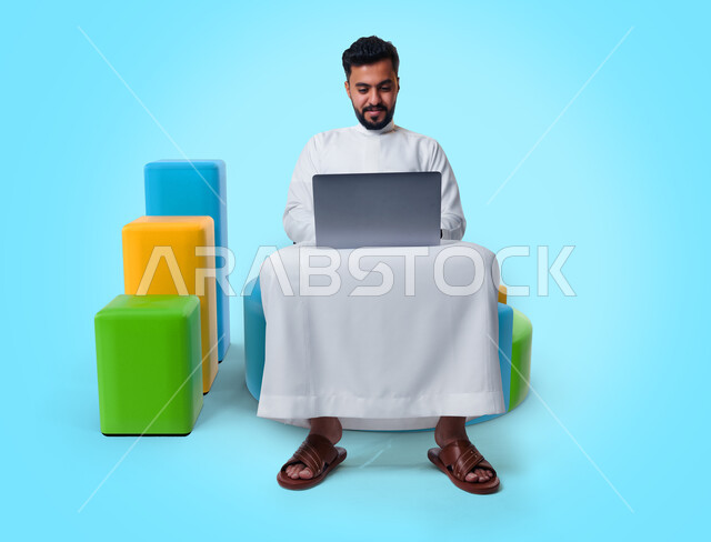 A Saudi Gulf Arab man using a laptop, completing work tasks, surfing the Internet, working remotely, e-marketing, graphics, the stock market, using electronic devices.