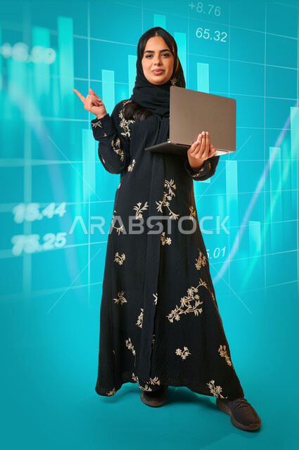 بورتريه لمرأة عربية خليجية سعودية تحمل جهاز الحاسوب المحمول ، صورة بالطول الكامل , رسومات بيانية هوولجرامية ، استراتيجات عمل ، بيانات و دراسات ، صعود الاسهم ،خلفية زرقاء