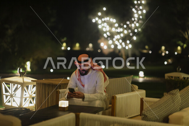 رجل عربي خليجي سعودي يستخدم الهاتف المحمول، تصفح الإنترنت، التواصل مع الأصدقاء، إستخدام وسائل التواصل الإجتماعي، هاتف محمول، استخدام تقنيات حديثة، دردشة الكترونية، منتزهات وحدائق