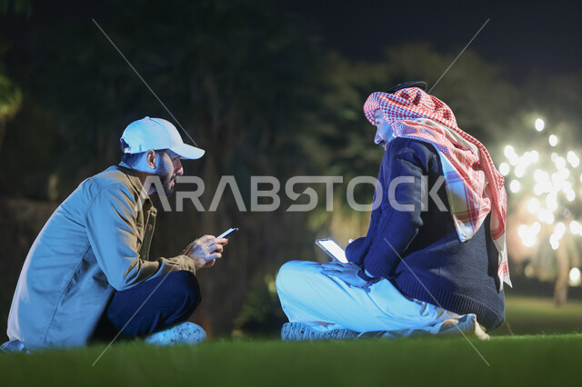 شابان عربيان خليجيان سعوديان يقضيان اوقات ممتعة، استخدام الهاتف المحمول، جلسة شبابية، صداقات شباب، نقاشات وحوارات، حدائق ومنتزهات