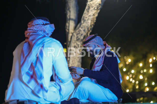 شابان عربيان خليجيان سعوديان يقضيان اوقات ممتعة، استخدام الهاتف المحمول، جلسة شبابية، صداقات شباب، نقاشات وحوارات، حدائق ومنتزهات