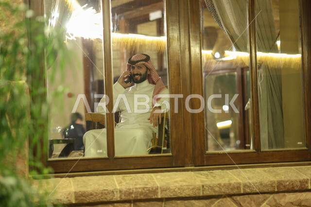 رجل عربي خليجي سعودي يقوم بإجراء مكالمة هاتفية، التواصل مع الأفراد، اتصال وتواصل، علاقات اجتماعية، دردشة وتعارف، التواصل الإجتماعي، جلسة سعودية