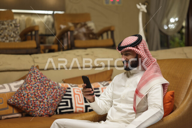 رجل عربي خليجي سعودي يستخدم الهاتف المحمول، تصفح الإنترنت، التواصل مع الأصدقاء، إستخدام وسائل التواصل الإجتماعي، هاتف محمول، دردشة الكترونية، استخدام تقنيات حديثة