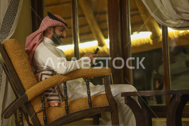 رجل عربي خليجي سعودي يستخدم الهاتف المحمول، تصفح الإنترنت، التواصل مع الأصدقاء، إستخدام وسائل التواصل الإجتماعي، هاتف محمول، دردشة الكترونية، استخدام تقنيات حديثة