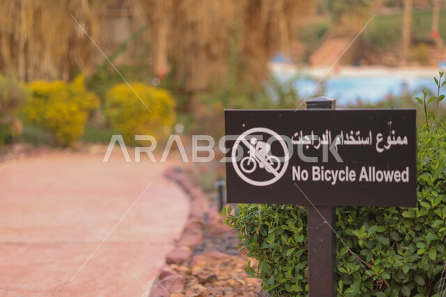 صورة مقربة للافتة تحذيرية، ممنوع دخول الدراجات، الاشجار والنباتات الخضراء، الحدائق العامة، الطبيعة الخضراء