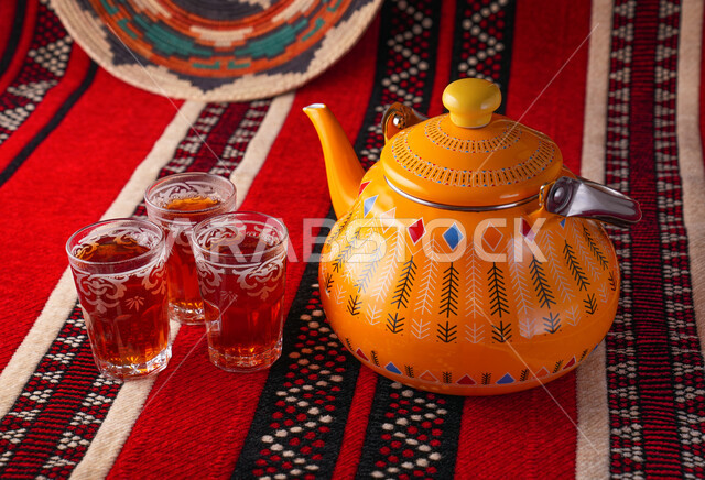 إبريق شاي اصفر اللون مع اكواب الشاي، المشروبات الساخنة، تقديم الشاي، الضيافة العربية، اكواب الشاي الاحمر