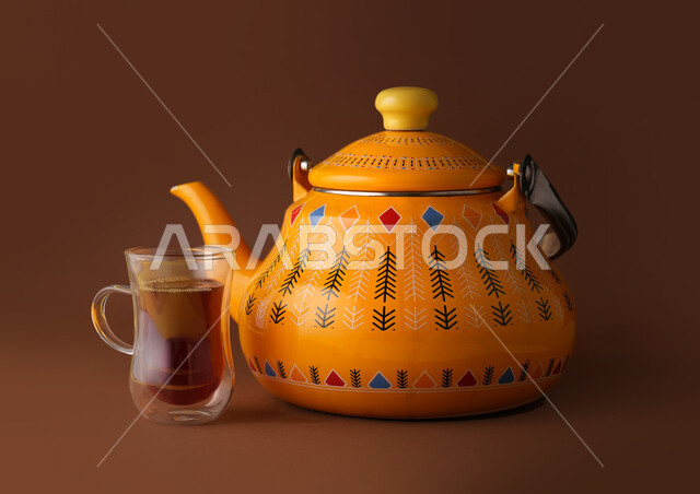 إبريق شاي اصفر اللون مع اكواب الشاي، المشروبات الساخنة، تقديم الشاي، الضيافة العربية، خلفية بنية