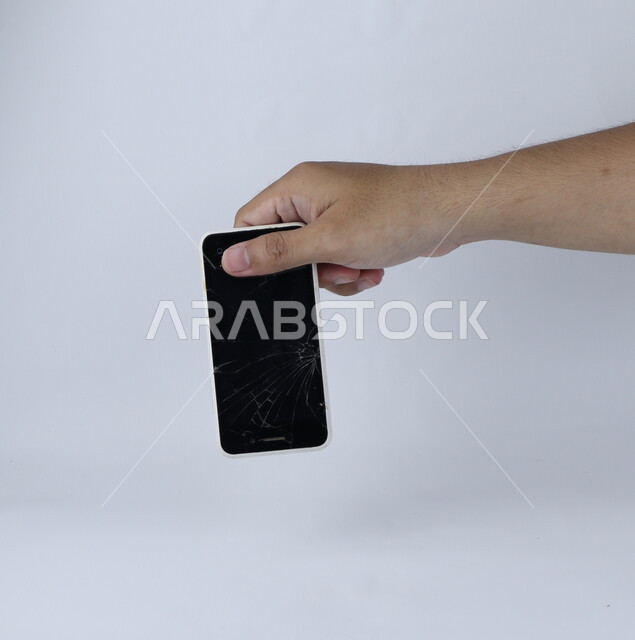 يد تحمل الهاتف المحمول ، الهاتف الخلوي بشاشة مكسورة ، خلفية بيضاء