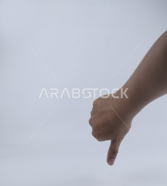 اصبع الإبهام لأسفل على خلفية بيضاء ، مفهوم لغة الإشارة ، وسيلة تواصل غير صوتية ، دلالة على عدم القبول والرضا والإعجاب