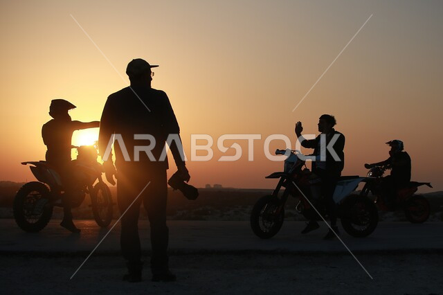 مجموعة من الشباب العرب الخليجيين السعوديين يستمتعون بركوب الدراجات النارية اثناء غروب الشمس،  نشاطات ترفيهية شباب ، سباقات وتحديات ، قيادة دباب ثنائي العجلات، دبابات نارية