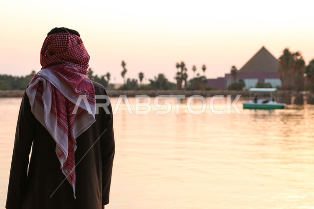 صورة من الخلف لرجل عربي خليجي سعودي يقضي اوقات ممتعة في احد الاماكن السياحية الترفيهية، بركة مائية، أنشطة ترفيهية، نزهه في الهواء الطلق