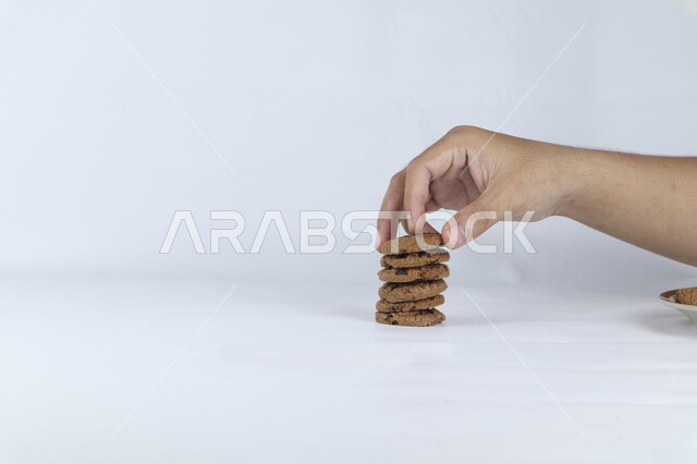 صوره مقربه ليد تأخذ حبه من رقائق البسكويت بالشوكولاته ، رقاقات البسكويت الهشة ، كوكيز ، بسكويت الشوكولاتة ، حلويات مخبوزة طازجة, خلفيه بيضاء