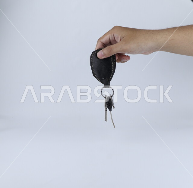 A hand holding a bunch of keys on a white background