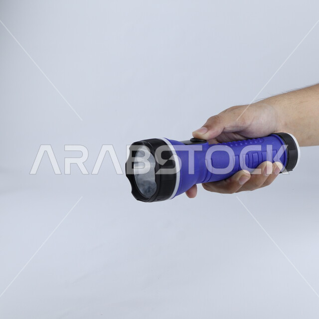 يد تحمل مصباح يدوي معزول على خلفية بيضاء ، كشاف ، المشعل الكهربائي