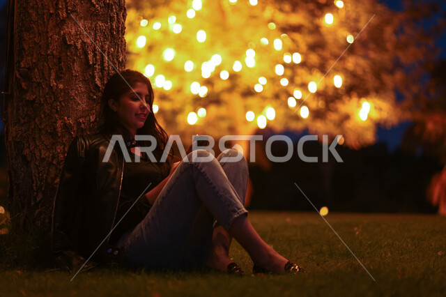 امرأة عربية خليجية سعودية تستخدم الهاتف المحمول، تصفح الإنترنت، هاتف محمول، دردشة الكترونية، استخدام تقنيات حديثة، حدائق ومنتزهات، اماكن هادئة، الجلوس في الهواء الطلق