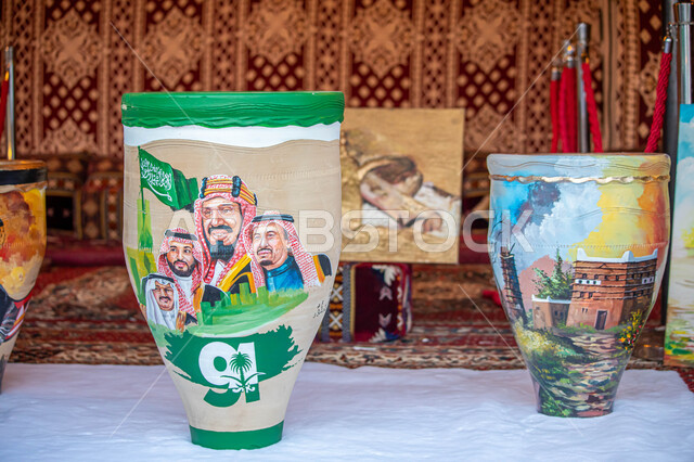 A close-up of traditional pottery, artistic drawings of the kings of Saudi Arabia, the kings of Al Saud, handicrafts, traditional folk crafts, the anniversary of the Saudi National Day, the Saudi National Day, the identity of the Saudi National Day 92