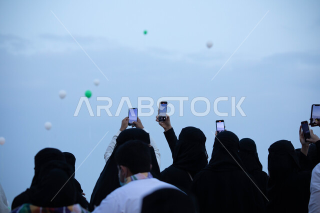 مجموعة من المواطنين العرب الخليجيين السعوديين يستخدمون الهواتف المحمولة، تصوير البالونات الطائرة، احياء ذكرى اليوم الوطني السعودي، العيد الوطني السعودي، احتفالات اليوم الوطني، هوية اليوم الوطني السعودي 92
