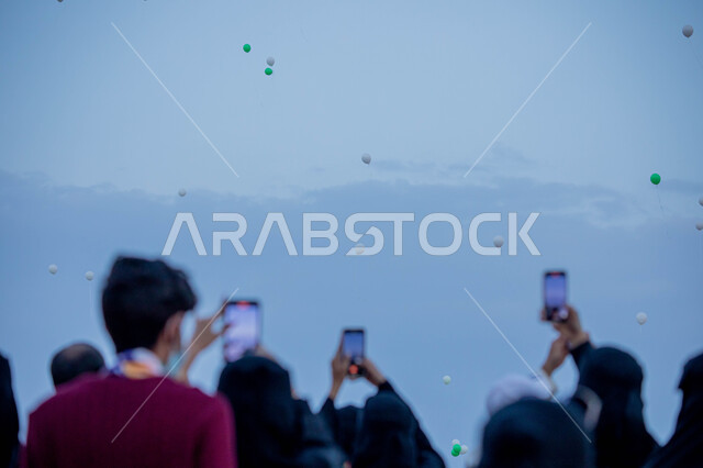 مجموعة من المواطنين العرب الخليجيين السعوديين يستخدمون الهواتف المحمولة، تصوير البالونات الطائرة، احياء ذكرى اليوم الوطني السعودي، العيد الوطني السعودي، احتفالات اليوم الوطني، هوية اليوم الوطني السعودي 92