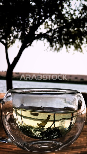 إنعكاس الطبيعة على كوب زجاجي شفاف ، خلفية ضبابية للطبيعة