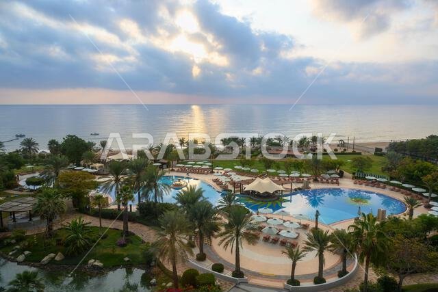 Sunset view over the pool at IHG Crowne Plaza Muscat, with palm trees ...