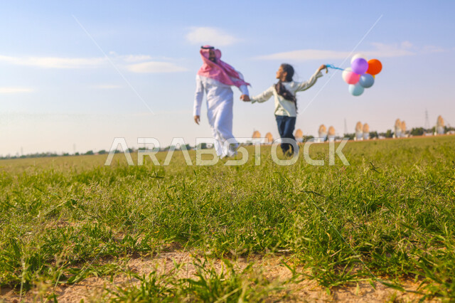 أب عربي سعودي خليجي يقضي اوقات ممتعة مع ابنته في إحدى الحدائق، بالونات ملونه, عطلة صيفية، نزهه في الهواء الطلق، جولة في الطبيعة الخضراء، مزرعة واستراحات، أنشطة ترفيهية عائلية