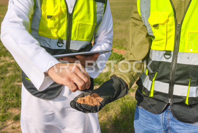 مهندسان زراعيان عربيان خليجيان سعوديان في حقل زراعي ، إرتداء خوذة وسترة الحماية، إتفاقيات و صفقات عمل، الاراضي والحقول الزراعية، آلات ومعدات الري المستقبلي، اذرع الري المحوري