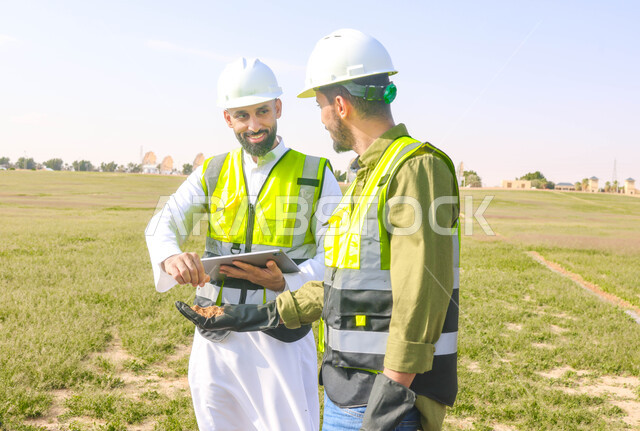 مهندسان زراعيان عربيان خليجيان سعوديان في حقل زراعي ، إرتداء خوذة وسترة الحماية، إتفاقيات و صفقات عمل، الاراضي والحقول الزراعية، آلات ومعدات الري المستقبلي، اذرع الري المحوري
