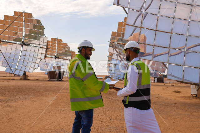مهندسان عربيان خليجيان سعوديان يشرفان على محطات الطاقة الشمسية ، إرتداء خوذة وسترة الحماية ، الإشراف على العمل، ستلايت، أنظمة الطاقة الشمسية، الطاقة المتجددة، ألواح شمسيه 