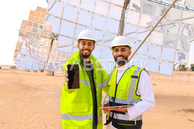 مهندسان عربيان خليجيان سعوديان يشرفان على محطات الطاقة الشمسية ، إرتداء خوذة وسترة الحماية ، الإشراف على العمل، ستلايت، أنظمة الطاقة الشمسية، الطاقة المتجددة، ألواح شمسيه 