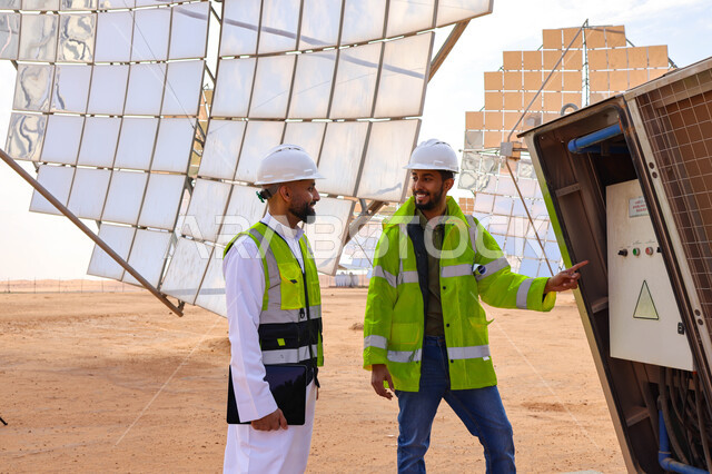 مهندسان عربيان خليجيان سعوديان يشرفان على محطات الطاقة الشمسية ، إرتداء خوذة وسترة الحماية ، الإشراف على العمل، ستلايت، أنظمة الطاقة الشمسية، الطاقة المتجددة، ألواح شمسيه 