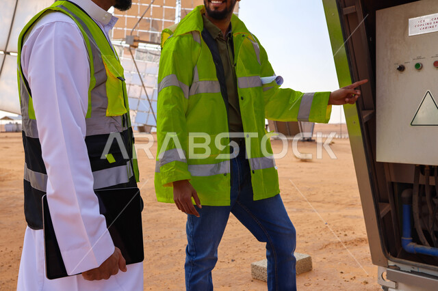 مهندسان عربيان خليجيان سعوديان يشرفان على محطات الطاقة الشمسية ، إرتداء خوذة وسترة الحماية ، الإشراف على العمل، ستلايت، أنظمة الطاقة الشمسية، الطاقة المتجددة، ألواح شمسيه 