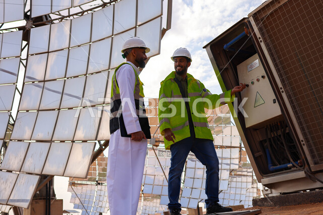 مهندسان عربيان خليجيان سعوديان يشرفان على محطات الطاقة الشمسية ، إرتداء خوذة وسترة الحماية ، الإشراف على العمل، ستلايت، أنظمة الطاقة الشمسية، الطاقة المتجددة، ألواح شمسيه 