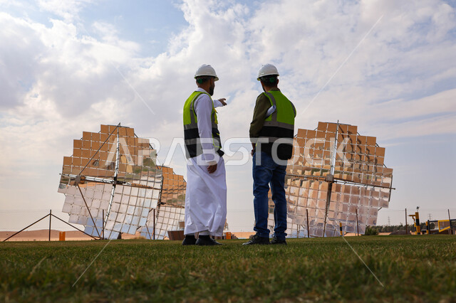 مهندسان عربيان خليجيان سعوديان يشرفان على محطات الطاقة الشمسية ، إرتداء خوذة وسترة الحماية ، الإشراف على العمل، ستلايت، أنظمة الطاقة الشمسية، الطاقة المتجددة، ألواح شمسيه 