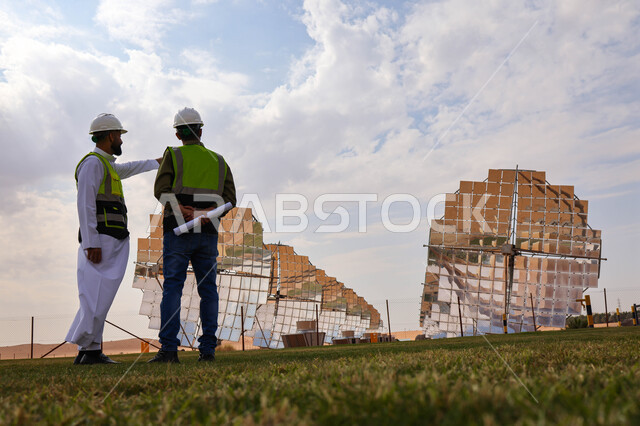 مهندسان عربيان خليجيان سعوديان يشرفان على محطات الطاقة الشمسية ، إرتداء خوذة وسترة الحماية ، الإشراف على العمل، ستلايت، أنظمة الطاقة الشمسية، الطاقة المتجددة، ألواح شمسيه 