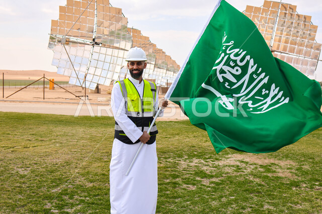 مهندس عربي خليجي سعودي يحمل علم المملكة، محطات الطاقة الشمسية، مستقبل الطاقة المتجددة، ألواح شمسية، اليوم الوطني السعودي 92، رؤية السعودية 2030
